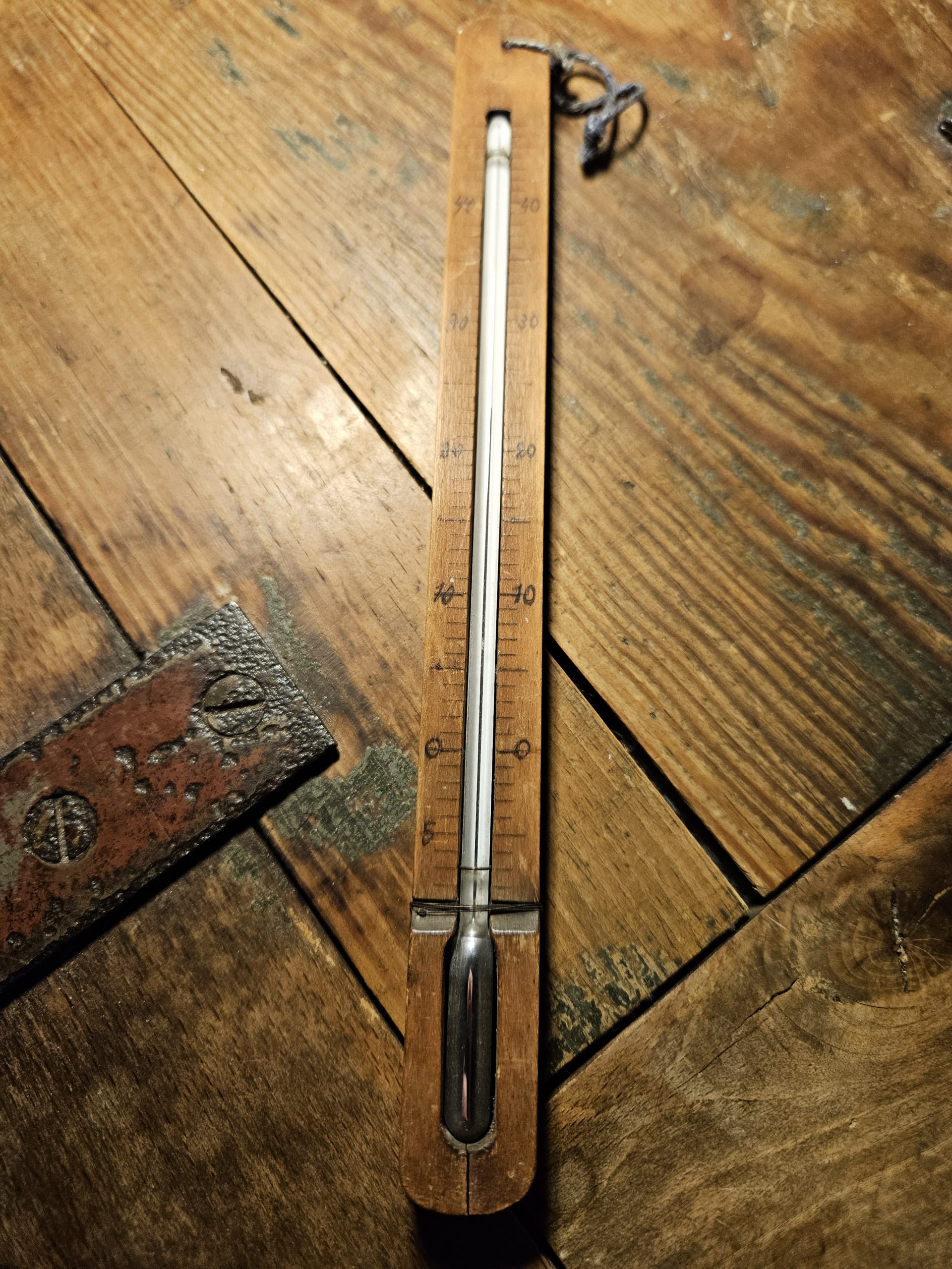 Holzthermometer mit einer Skala in Celsius, vermutlich ein Quecksilber- oder Alkoholthermometer.